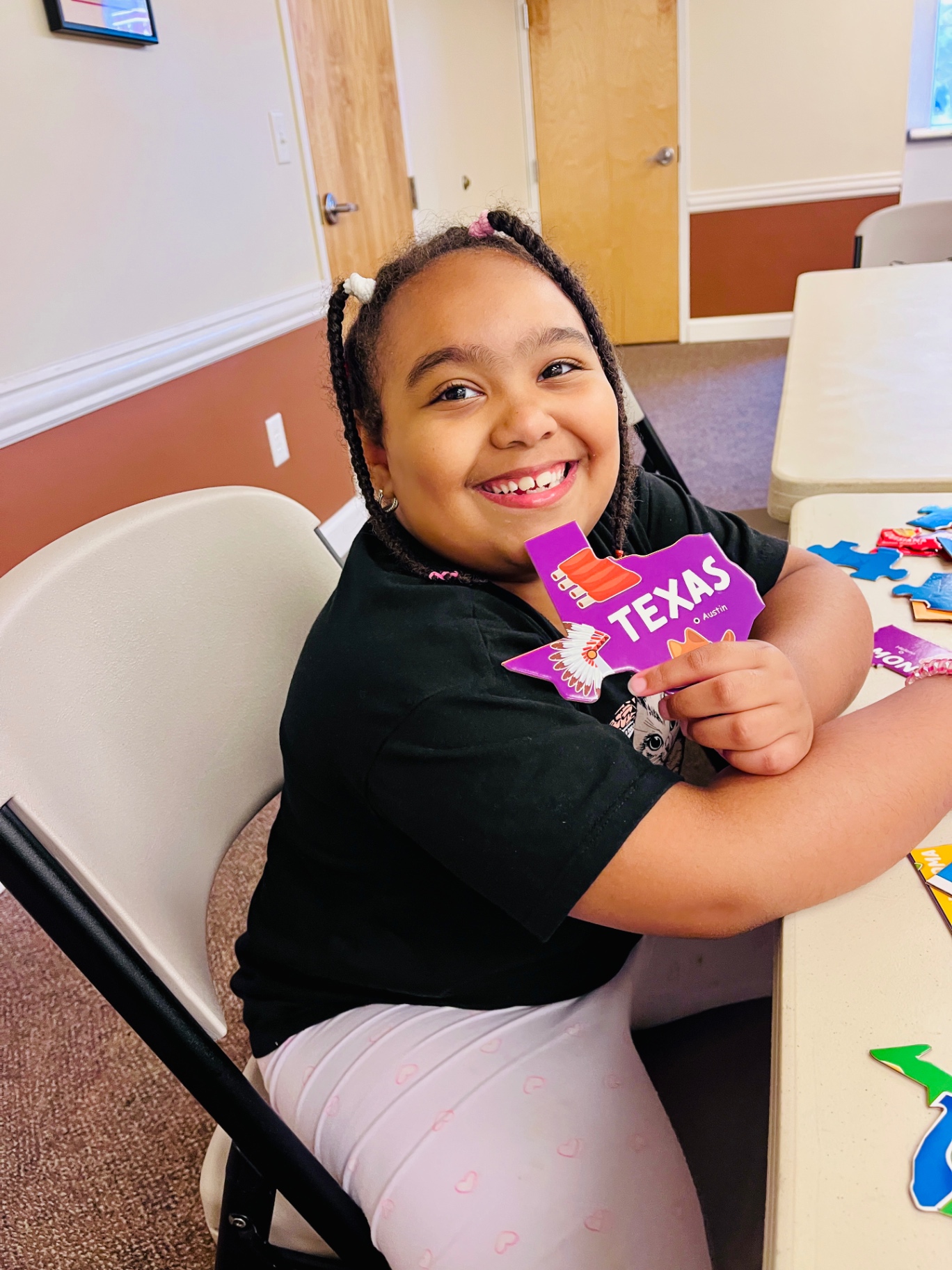 A smiling student completing a colorful geography puzzle